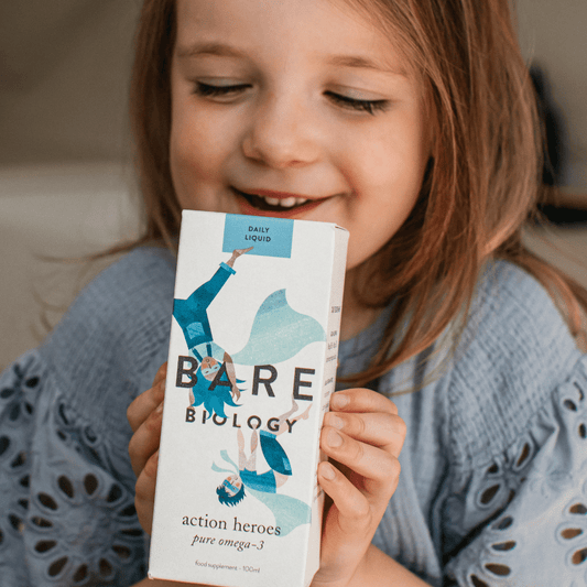 A child holding a box of supplements with a smile.