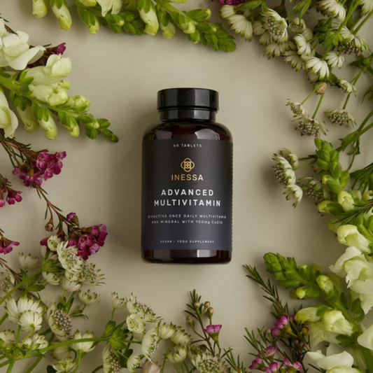 A bottle of Primal Ayurveda Multivitamin surrounded by assorted flowers.