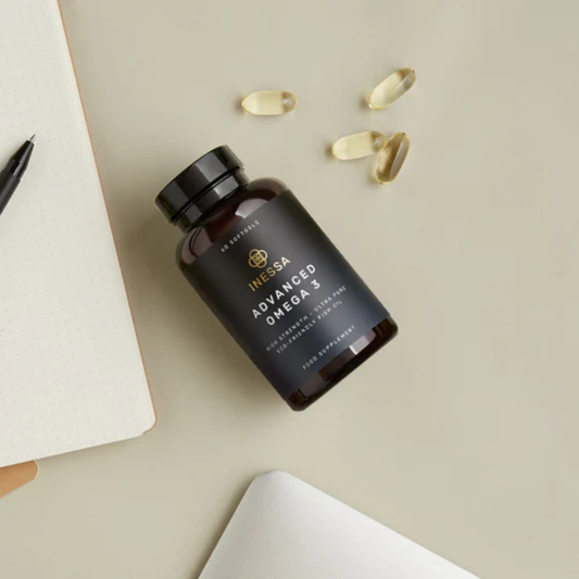 A bottle of supplements with several capsules beside it.