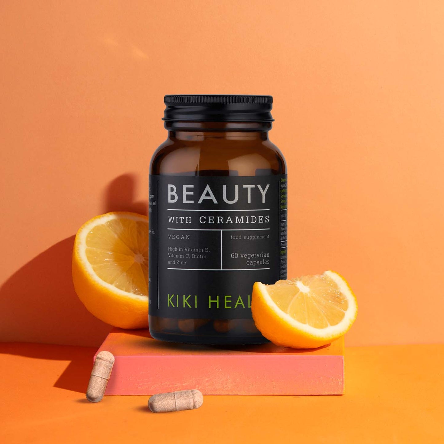 A bottle of beauty supplements with sliced oranges and capsules.