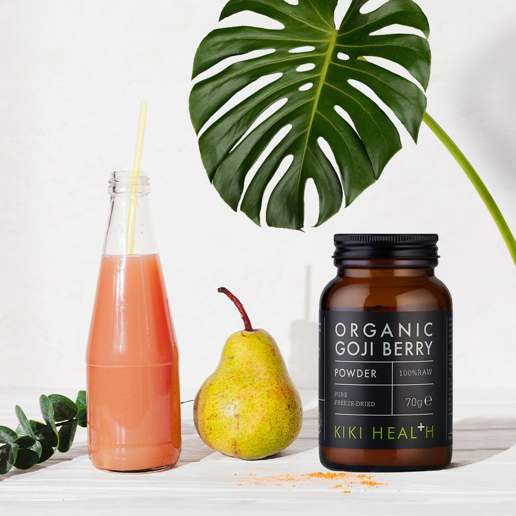 A bottle of juice, a pear, and a jar of organic capsules.