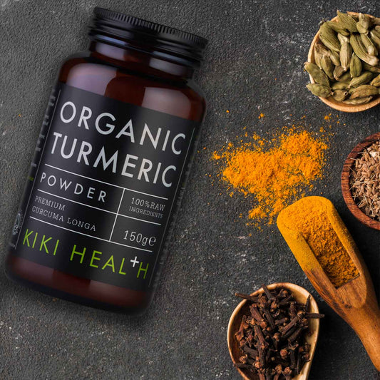 A bottle of organic turmeric with spices and a wooden spoon.