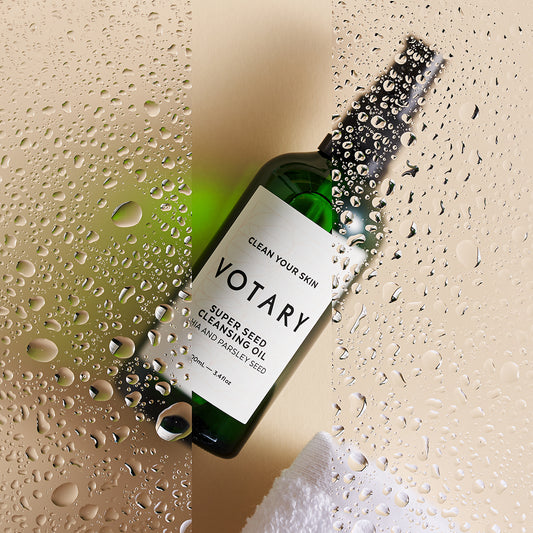 A green bottle of cleansing oil with droplets on glass.
